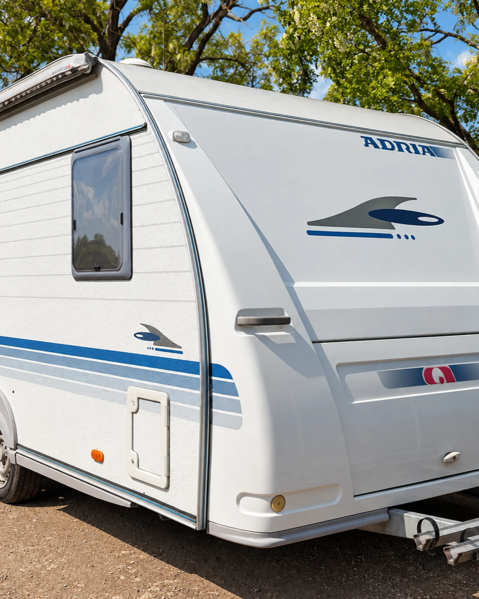 Bočný pohľad na karavan Adria 450 v tieni stromov